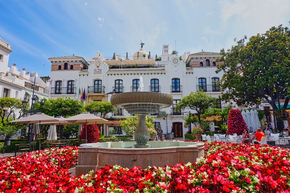 Foto von Estepona mit roten Blumen im vordergrund