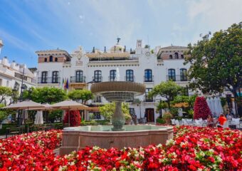 Foto von Estepona mit roten Blumen im vordergrund